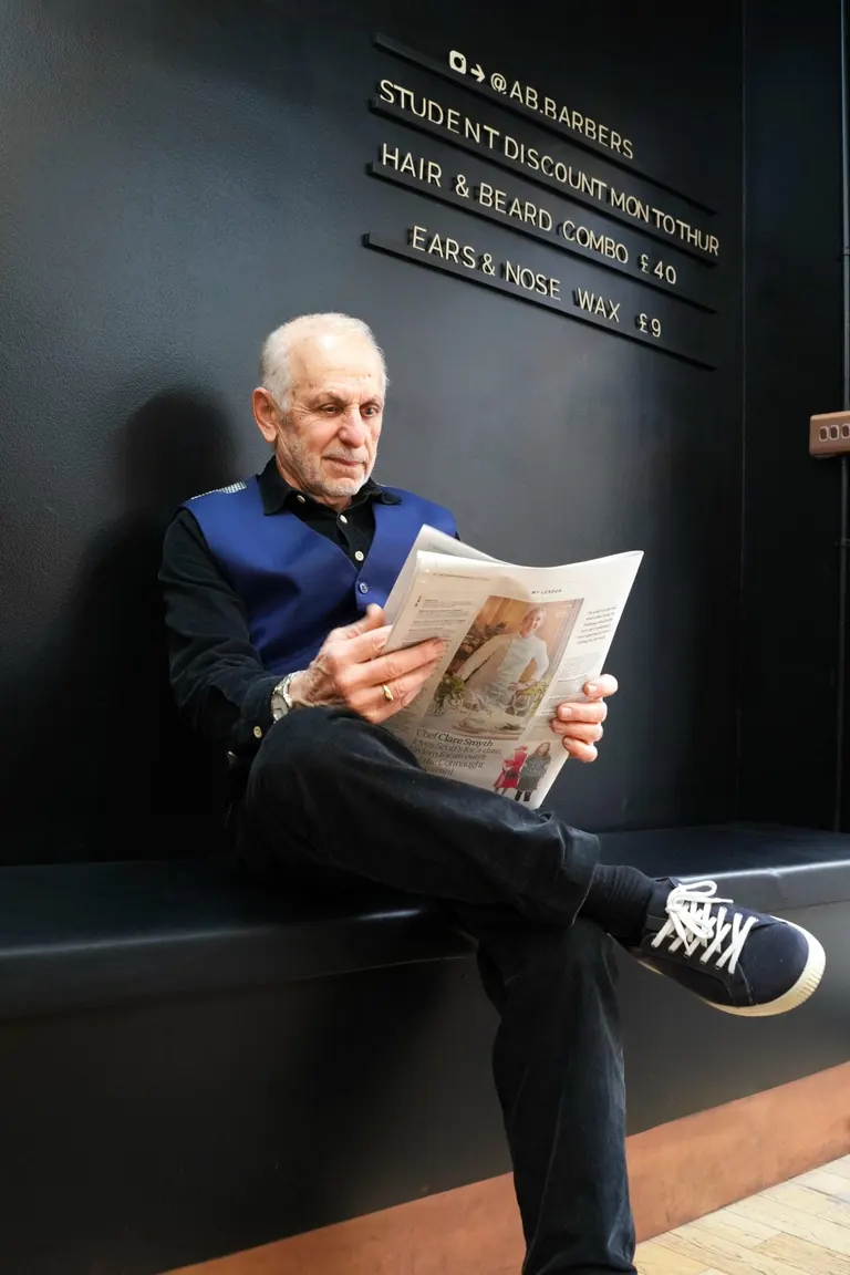 AB Barbers, Putney. A regular reads the paper on the bench.