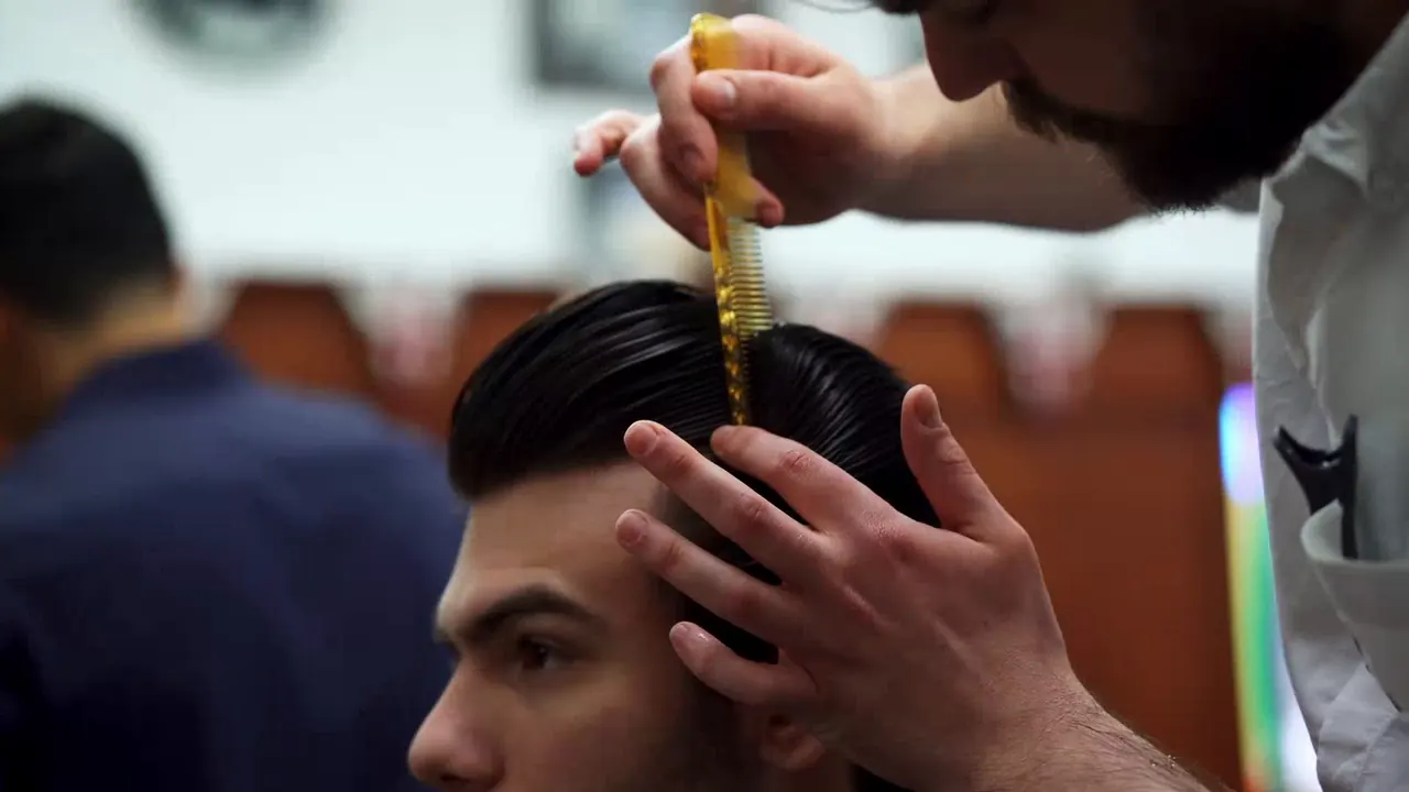 A Pall Mall Barbers barber combs a customer's hair into shape.