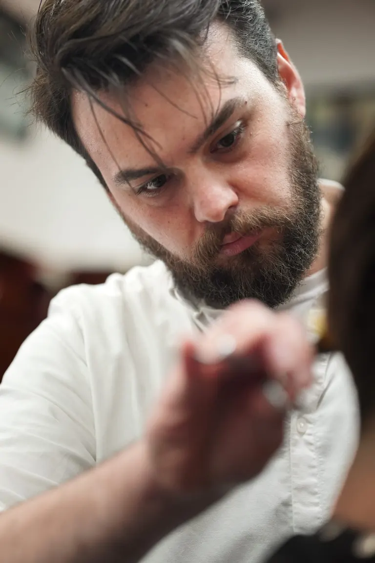 Pall Mall Barbers, London. A Pall Mall barber leans in close, eyes on the line.