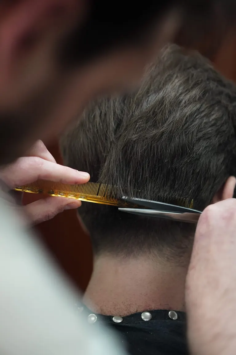 Pall Mall Barbers, London. A comb lifts the hair at the nape before the scissors go in.