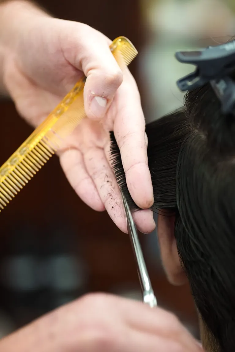 Pall Mall Barbers, London. Scissors and a comb take length off the back.