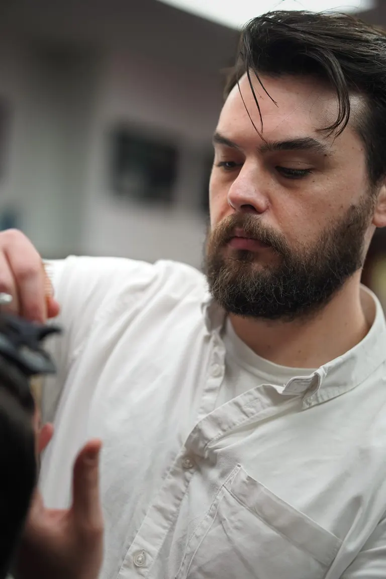 Pall Mall Barbers, London. The barber checks his work between passes.