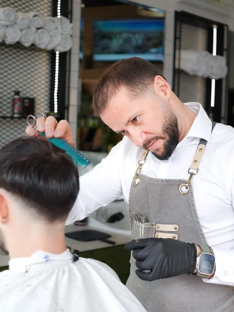 A barber at The Axe Club combing through a customer's cut