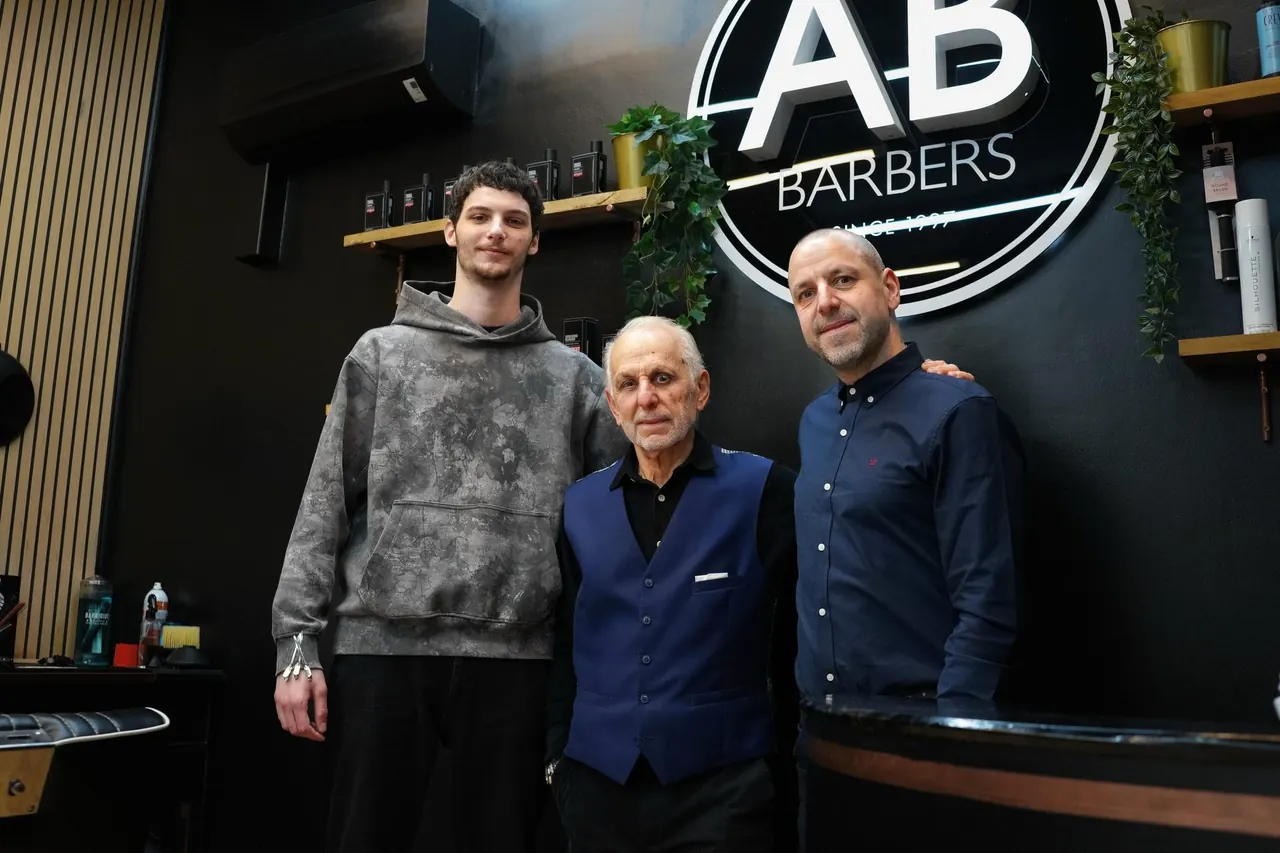 Three barbers from AB Barbers standing under the shop's logo.