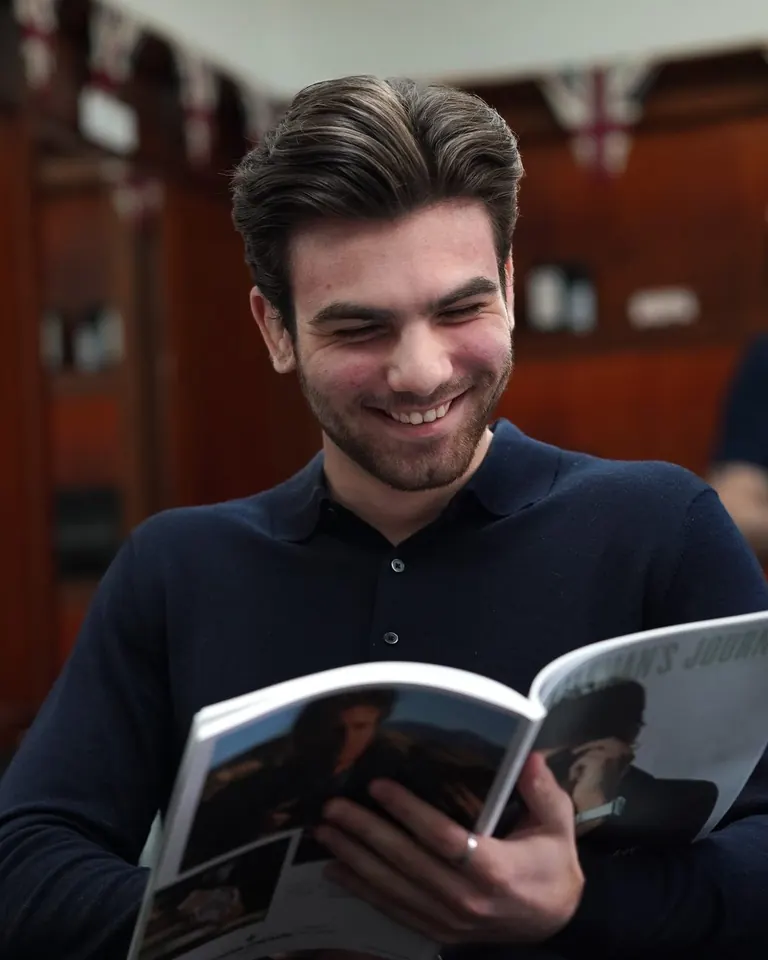 A customer laughing over a magazine while he waits at Pall Mall Barbers.