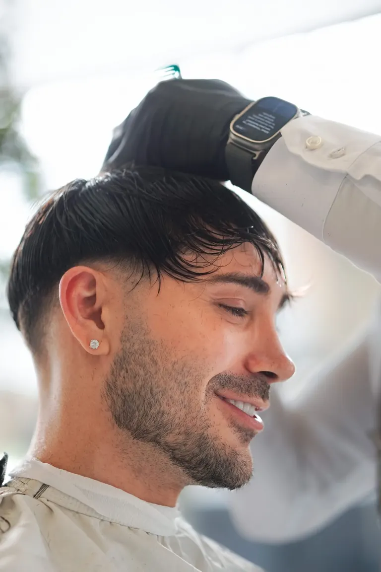 A customer at The Axe Club smiling as his fringe is styled.